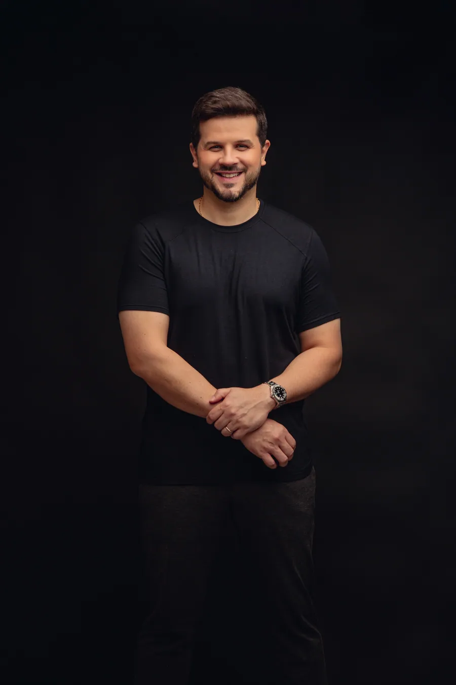Retrato de Carlos Eduardo Avelino, de camiseta preta, sorrindo, sobre fundo escuro.